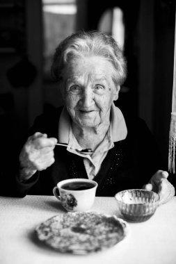 Çay içen yaşlı bir kadın. Siyah beyaz portre.