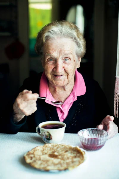 Gammal Kvinna Dricker Med Bakverk Hemma — Stockfoto