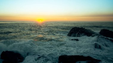 Muhteşem bir günbatımında okyanus sörfü manzarası.