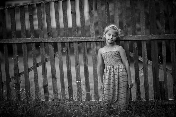 小女孩站在村子的栅栏旁边 黑白照片 — 图库照片