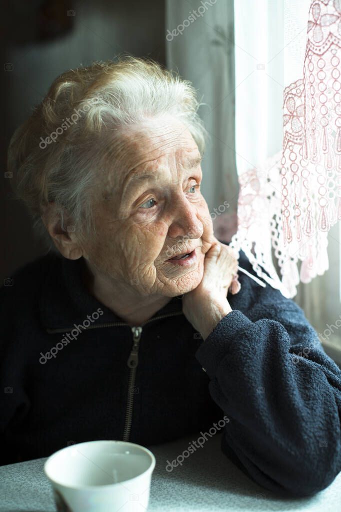 An old woman looks dreamily out of the window.