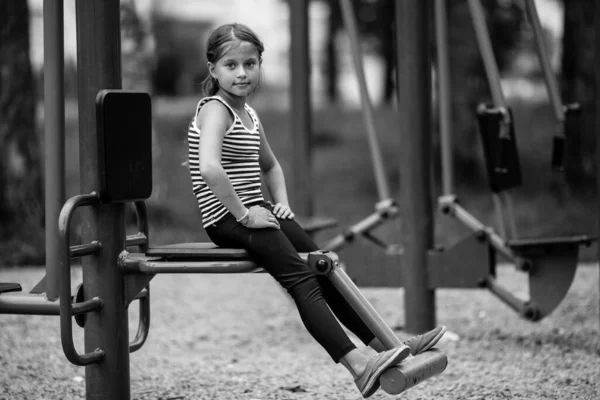 Klein Schattig Meisje Een Trainer Machine Speelplaats Buiten Zwart Wit — Stockfoto