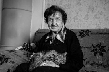 Evinde kedisi olan yaşlı bir kadın. Siyah beyaz fotoğraf.