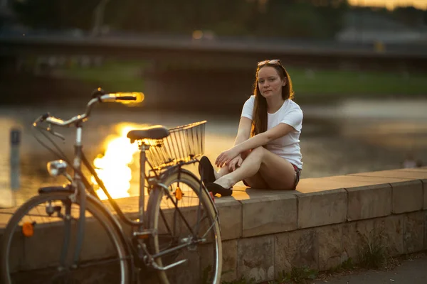 夕暮れ時に堤防の上に自転車を持つ10代の少女 — ストック写真