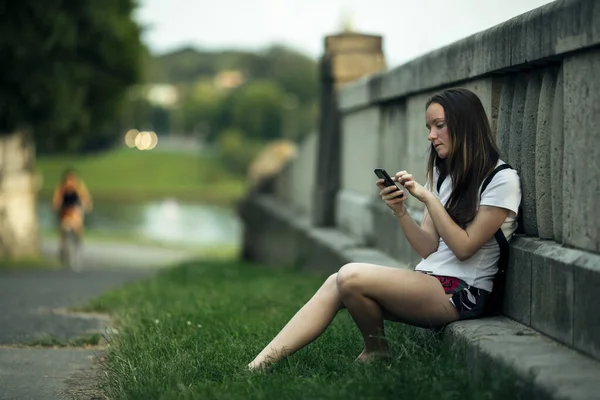 Genç Bir Kız Dışarıda Otururken Telefonuyla Yazı Yazıyor — Stok fotoğraf