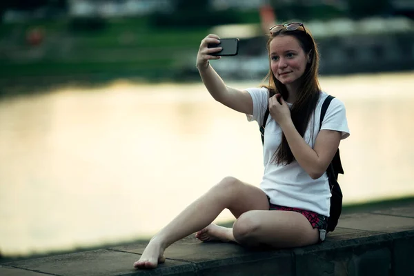 Genç Bir Kız Nehir Kenarında Otururken Selfie Çekiyor — Stok fotoğraf