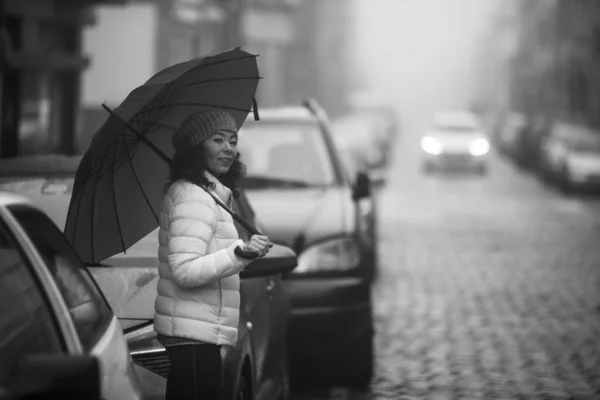 A woman stands in the street in cloudy weather. Black and white photo.