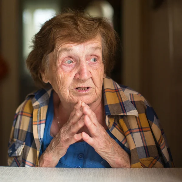 Пожилая женщина сидит за столом — стоковое фото