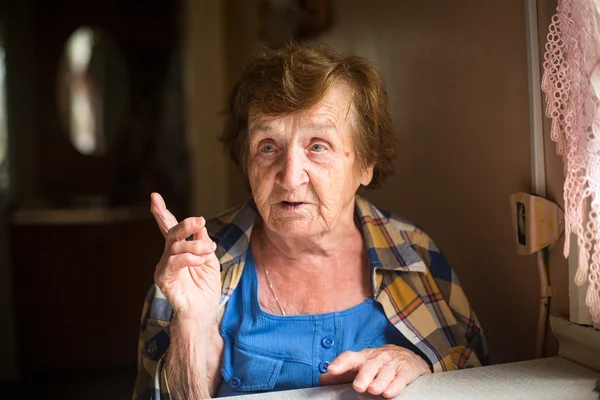 Femme âgée assise à table — Photo