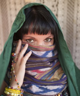 Kızın yüzünü bir örtü ile kapsar.