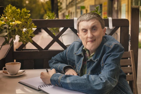 Disabled man writing in a notebook — Stock Photo, Image