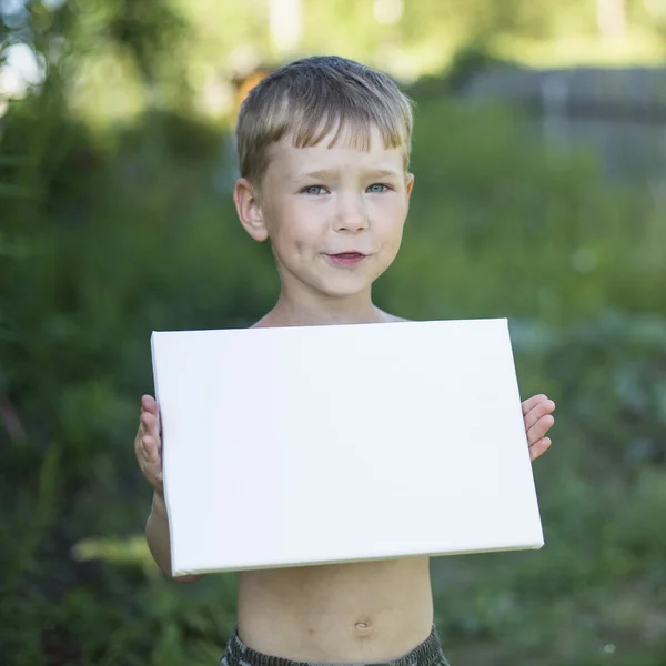 Kleiner Junge hält sauberes weißes Blatt Papier — Stockfoto