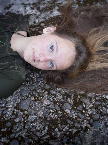 石造りの背景の上に横たわる美しい少女. — ストック写真
