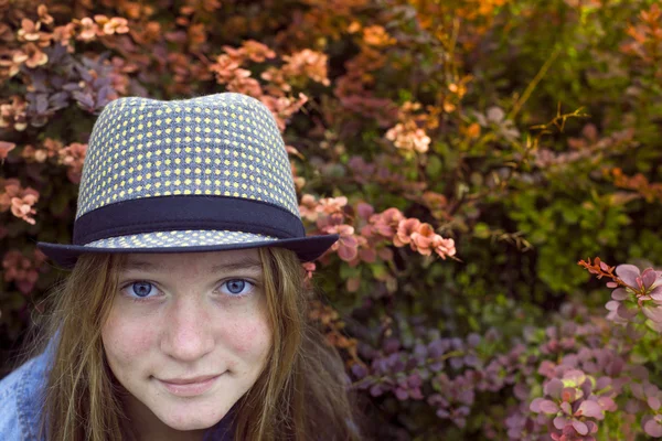 Girl with blue eyes in a hat in the garden. Stock Picture