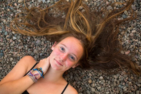 Young girl lying on pebbles — Stock Photo, Image
