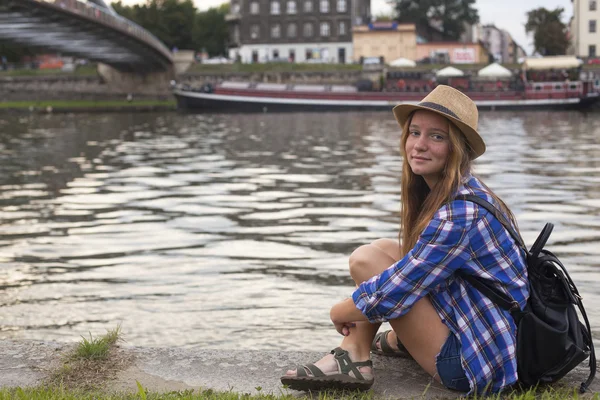 Meisje, zittend op stenen embankment — Stockfoto