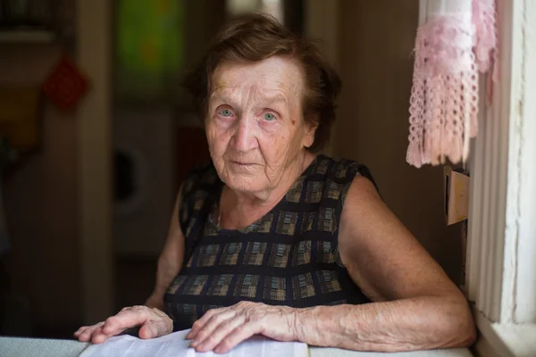 Femme âgée assise à table — Photo