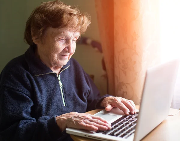 Grootmoeder werkt met een laptop. — Stockfoto