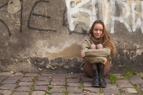 Girl sitting near  wall — Stock Photo, Image