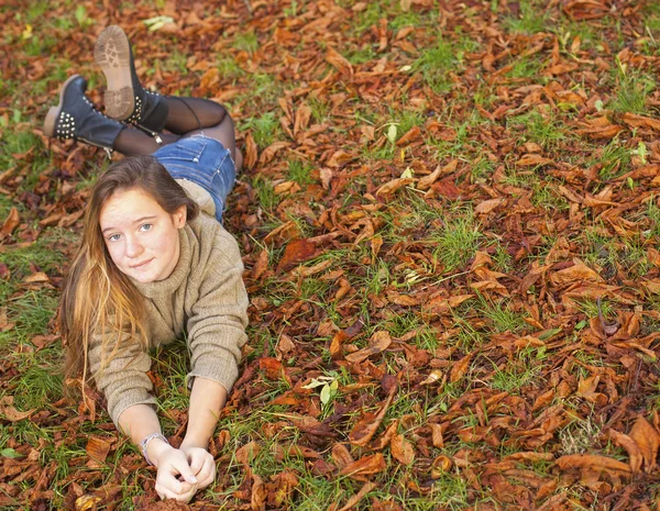 Menina deitada nas folhas — Fotografia de Stock