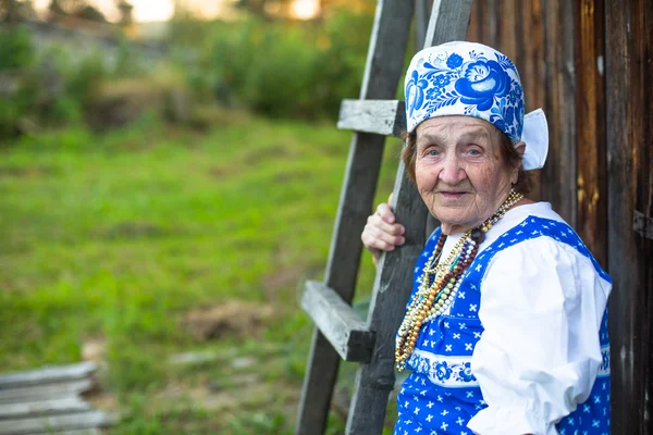 Old woman posing at village in folk costume — Stock Photo, Image