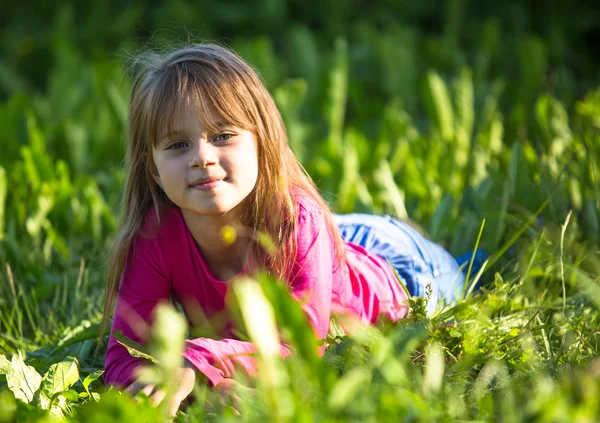 Sevimli küçük kız yeşil çim döşeme — Stok fotoğraf