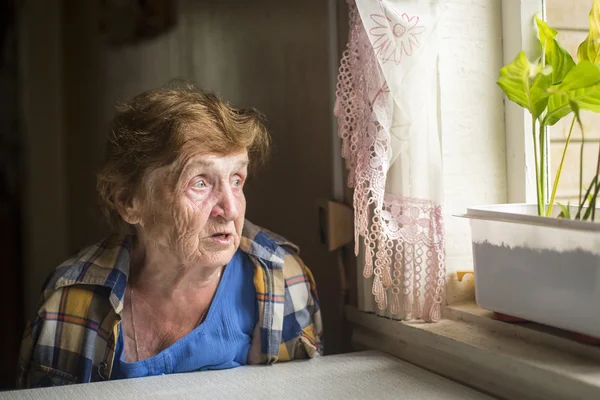 Vecchia donna sola vicino a una finestra — Foto Stock