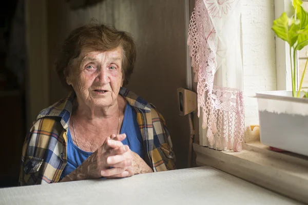 Vieille femme seule près d'une fenêtre — Photo