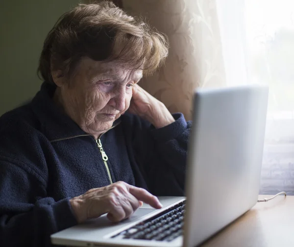 Old woman works on laptop — Stock Photo, Image