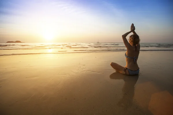 Девушка сидит на берегу моря и медитирует — стоковое фото