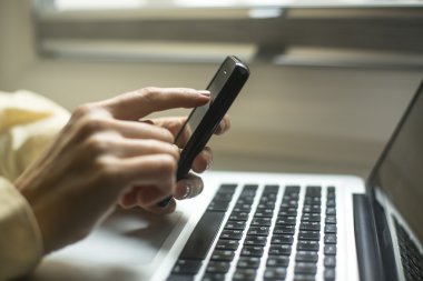Laptop ve cep telefonu kullanan kadın