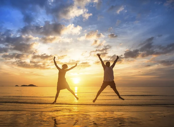 Paar springt am Strand auf — Stockfoto