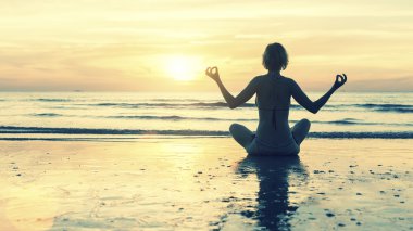 Yoga gün batımı sırasında sahilde.