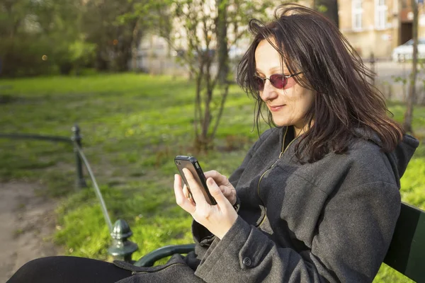 Mladá žena sedí na lavičce v parku — Stock fotografie