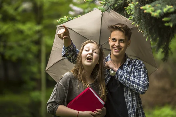 Giovane ragazzo e ragazza sotto un ombrello — Foto Stock