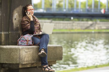 Genç bir kadın dizüstü bilgisayarla oturuyor