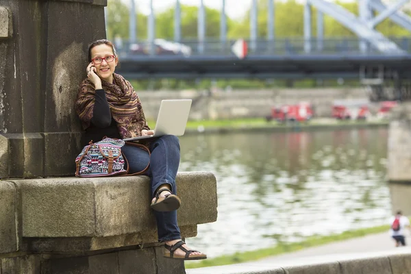 Woman with laptop sitting outdoors — Stok fotoğraf