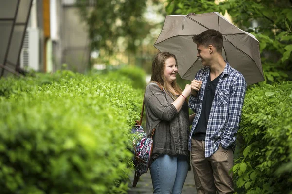 Guy and girl talking under umbrella — Stockfoto