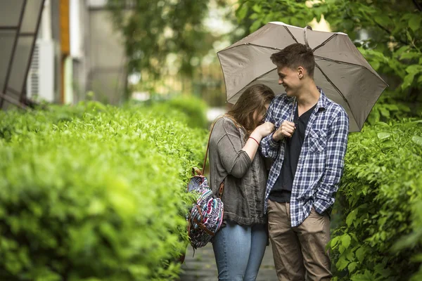 Cara e menina falando sob guarda-chuva . Fotos De Bancos De Imagens