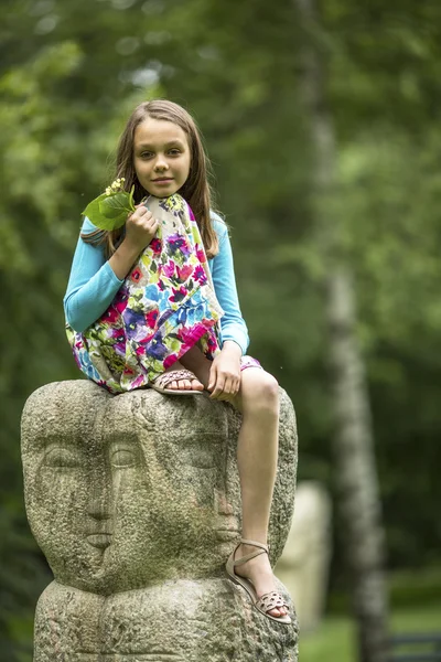 Little girl sitting on stone totem — Stok fotoğraf