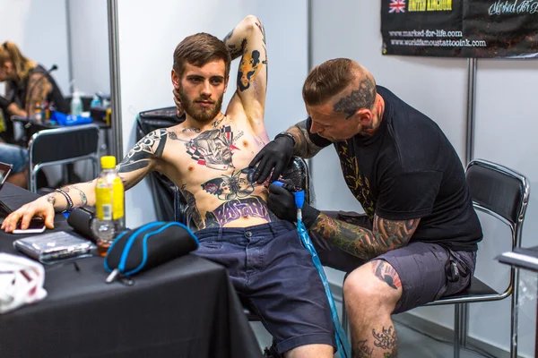 People make tattoos at Tattoo Convention — Stock Fotó