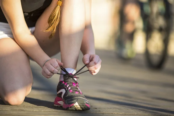 Девушка завязывая шнурки спортивная обувь — стоковое фото