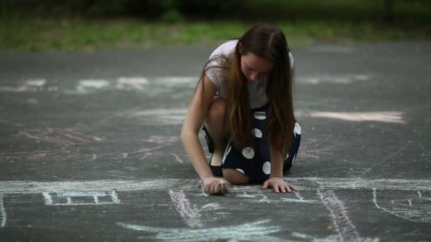 Tonårs flicka ritar med krita på trottoaren — Stockvideo