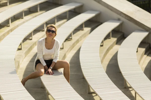 Young beautiful woman sitting on benches — Stockfoto