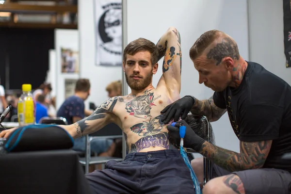 People make tattoos at Tattoo Convention — Stock Fotó