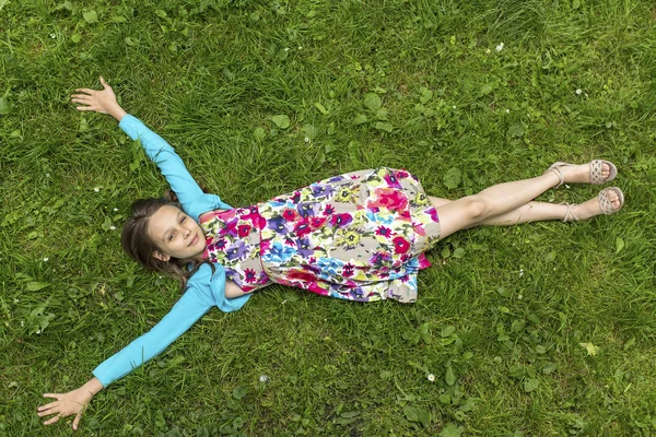 Niedliches kleines Mädchen liegt auf Gras — Stockfoto