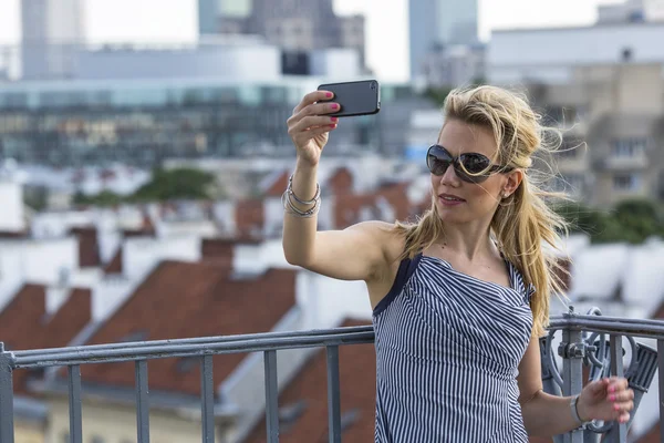 Blonde in sunglasses taking a selfie on smartphone — Stock Photo, Image