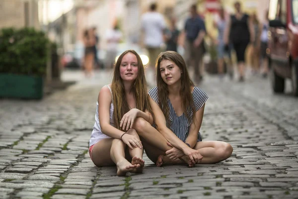 Dziewczyny siedzą na kamienny bruk. — Zdjęcie stockowe