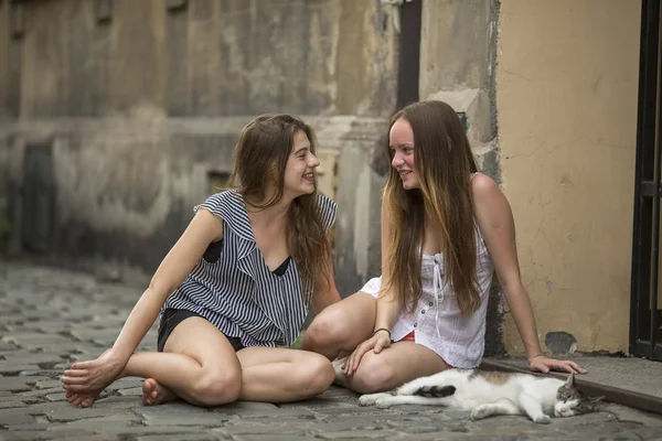 Vriendinnen met een kat op de stoep zitten — Stockfoto