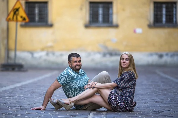 Mladý pár sedí na chodníku — Stock fotografie